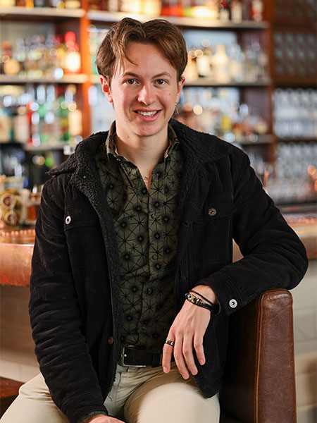 Ein Portrait einer Person vor einem Regal voller Gläser