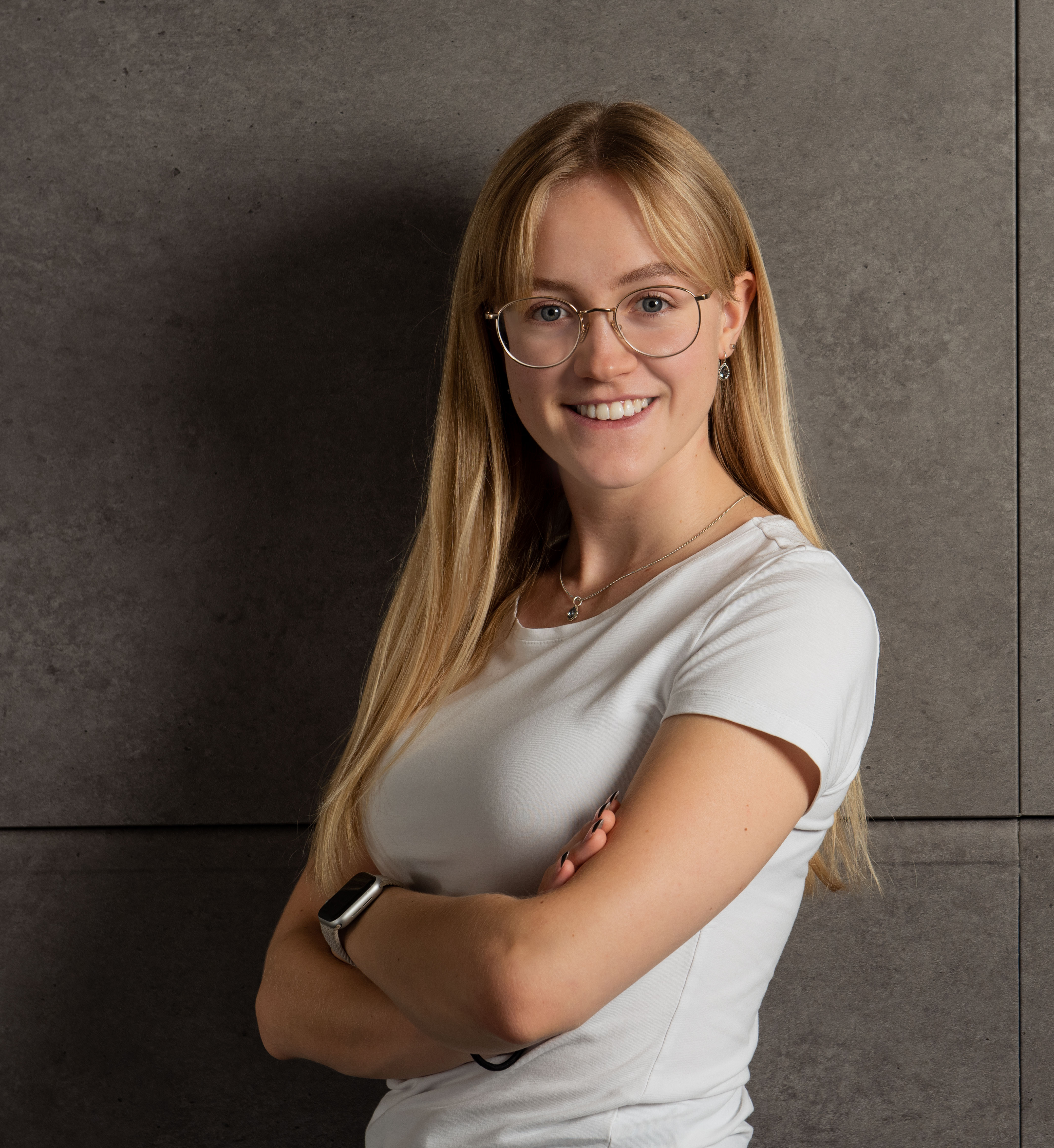 Tanja mit verschränkten Armen vor einer Wand.
